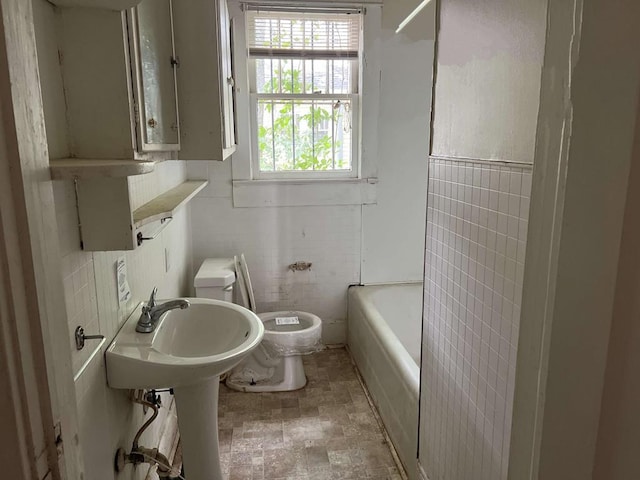 bathroom with toilet and tile walls