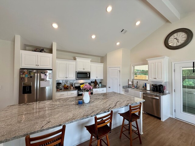 103 Neenan Dr, Enterprise, AL 36330 - kitchen featuring appliances with stainless steel finishes, a kitchen bar, decorative backsplash, white cabinetry, and beam ceiling