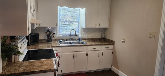 kitchen with stainless steel microwave, backsplash, range with electric stovetop, and a sink