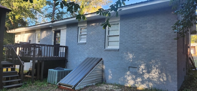 view of side of property featuring brick siding, central AC unit, a deck, and stairs