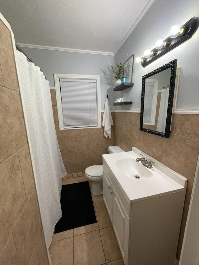 full bath featuring toilet, vanity, ornamental molding, tile patterned floors, and tile walls