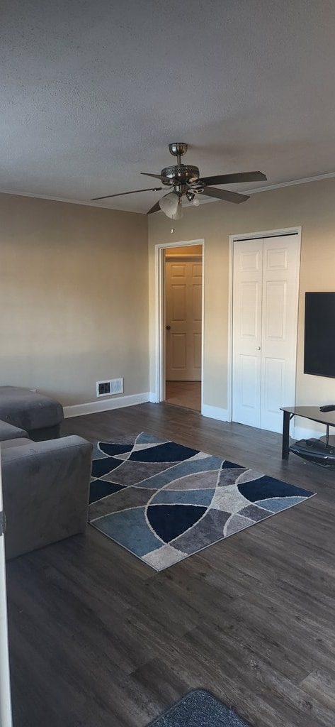 living room featuring visible vents, baseboards, wood finished floors, a textured ceiling, and a ceiling fan