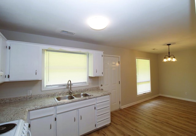1125 Garden Ln, Dothan, AL 36301 - kitchen with stove, light countertops, white cabinetry, light wood-style floors, and a chandelier