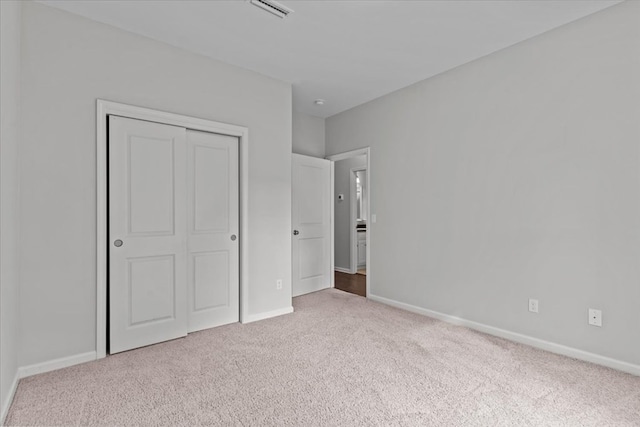 unfurnished bedroom featuring a closet and light colored carpet