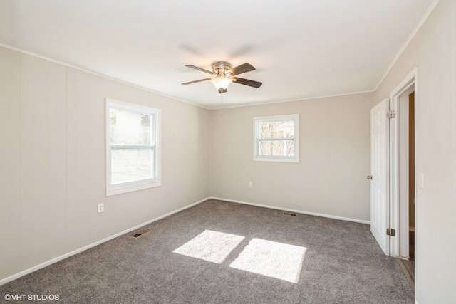 empty room featuring ceiling fan, carpet floors, and a wealth of natural light