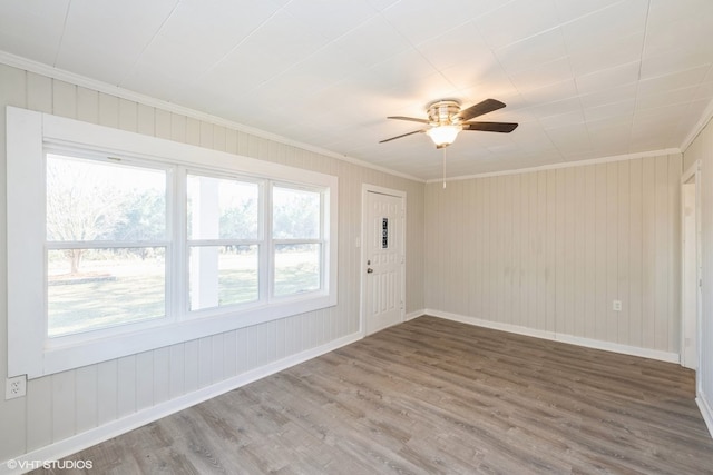 empty room with ceiling fan, wood-type flooring, and crown molding