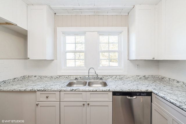 kitchen with decorative backsplash, white cabinetry, stainless steel dishwasher, and sink