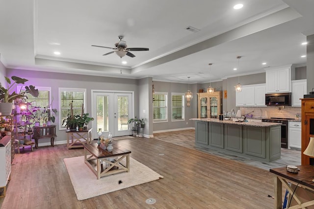 living room featuring hardwood / wood-style flooring, ornamental molding, a raised ceiling, and french doors