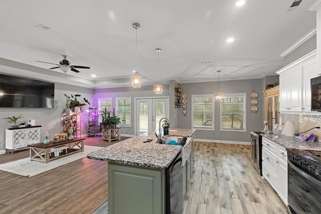 kitchen with white cabinetry, green cabinets, ornamental molding, and a center island with sink