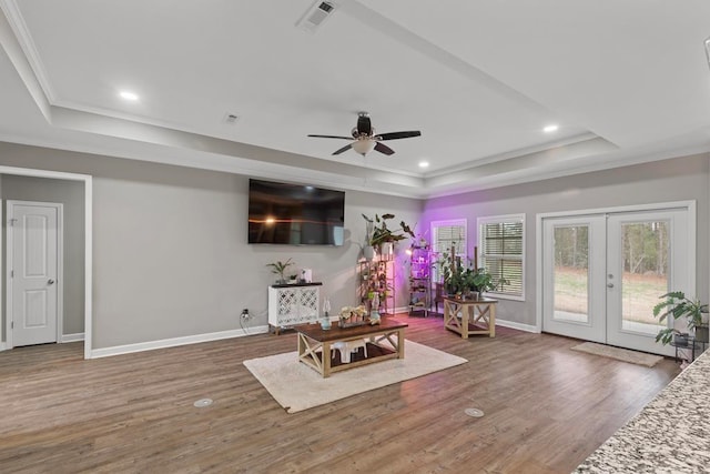 living area with a raised ceiling, crown molding, dark hardwood / wood-style floors, and french doors