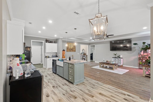 kitchen with hanging light fixtures, stainless steel appliances, white cabinets, a center island with sink, and light wood-type flooring