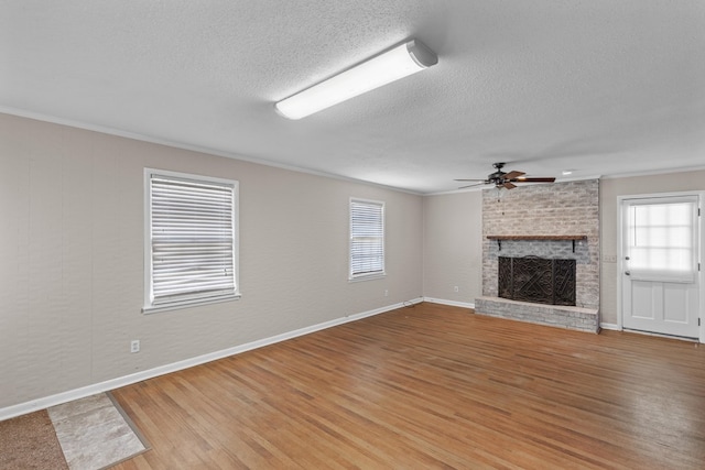 unfurnished living room featuring wood-type flooring, plenty of natural light, ornamental molding, and a fireplace