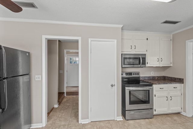 kitchen with white cabinetry, light tile patterned floors, stainless steel appliances, crown molding, and a textured ceiling