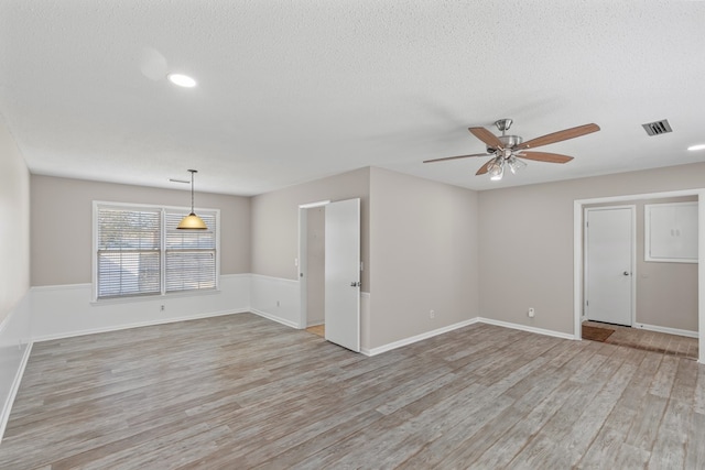 empty room with ceiling fan, a textured ceiling, and light wood-type flooring