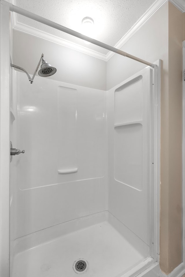 bathroom featuring a shower, ornamental molding, and a textured ceiling