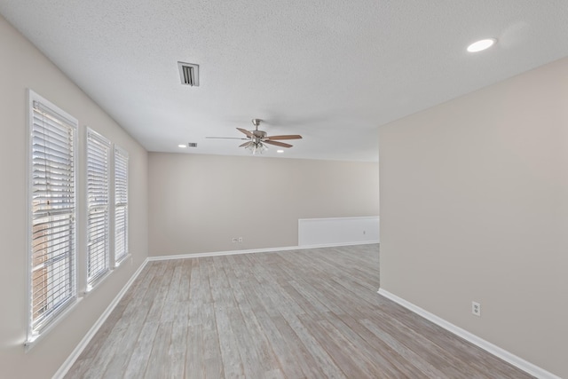 spare room with ceiling fan, a healthy amount of sunlight, a textured ceiling, and light wood-type flooring