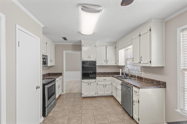 kitchen featuring sink, crown molding, light tile patterned floors, appliances with stainless steel finishes, and white cabinets