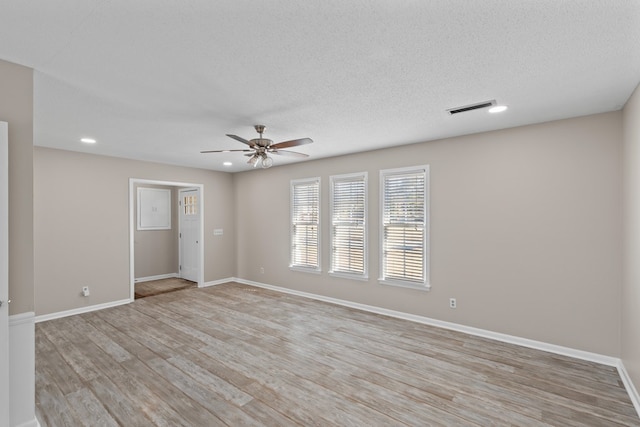 unfurnished room with ceiling fan, light hardwood / wood-style flooring, and a textured ceiling