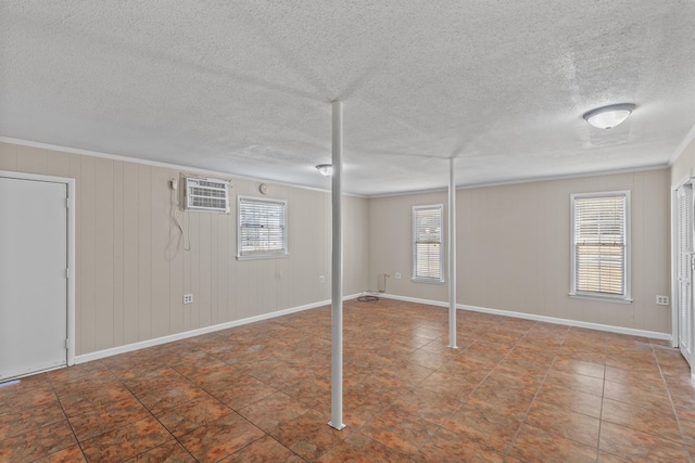 basement featuring ornamental molding, a wall mounted AC, a healthy amount of sunlight, and wood walls