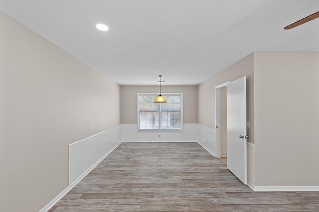 unfurnished dining area with light hardwood / wood-style flooring and a textured ceiling