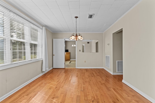 unfurnished dining area with an inviting chandelier, light hardwood / wood-style flooring, and crown molding