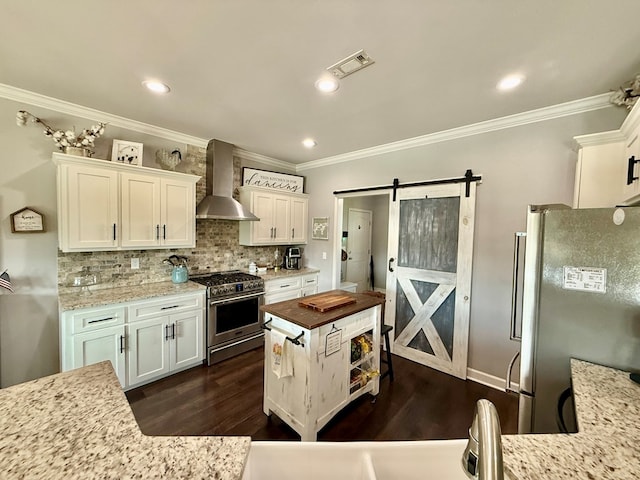 1243 Silcox Rd, Ashford, AL 36312 - kitchen featuring stainless steel appliances, wall chimney range hood, crown molding, a barn door, and dark wood-style flooring