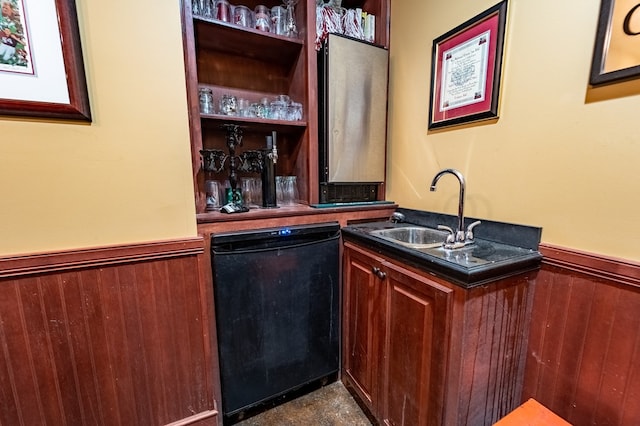 bar featuring dishwasher, wood walls, and sink