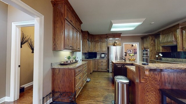 kitchen with a kitchen bar, light stone countertops, ornamental molding, and appliances with stainless steel finishes