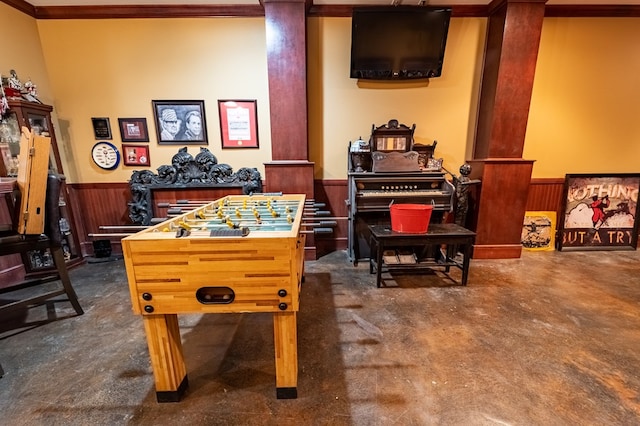 rec room featuring wood walls, crown molding, and dark carpet