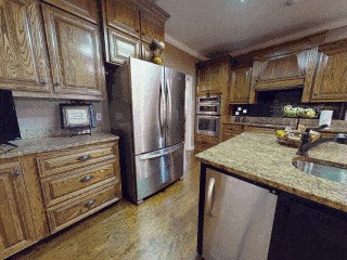 kitchen with light stone countertops, light wood-type flooring, ornamental molding, stainless steel appliances, and sink