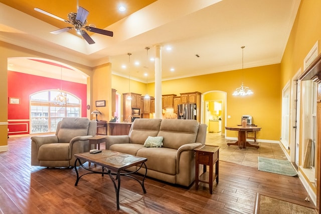 living room with hardwood / wood-style flooring, ceiling fan with notable chandelier, and crown molding