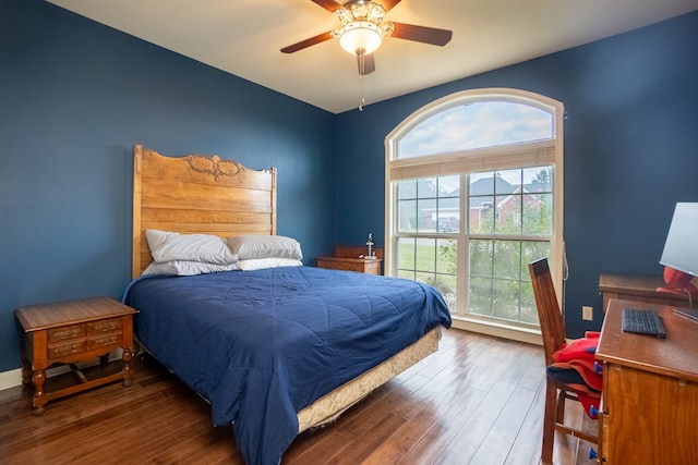 bedroom featuring multiple windows, dark hardwood / wood-style floors, and ceiling fan