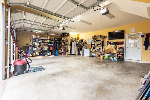 garage featuring a workshop area, white refrigerator, and a garage door opener