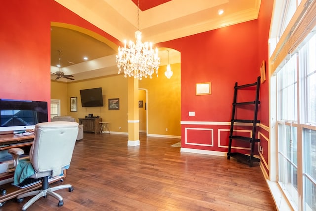 office space with crown molding, hardwood / wood-style floors, a towering ceiling, and ceiling fan with notable chandelier