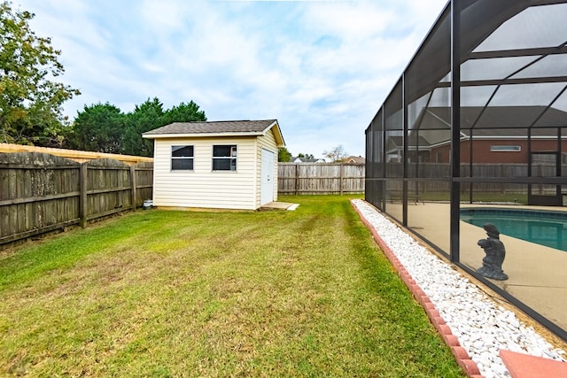 view of yard with a lanai, a fenced in pool, and an outbuilding