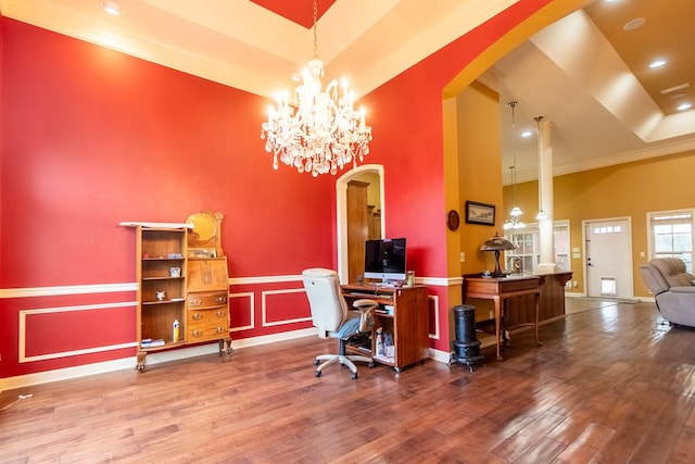 office featuring wood-type flooring, a towering ceiling, an inviting chandelier, and crown molding