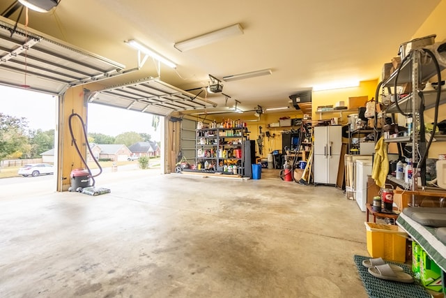 garage with a workshop area, white fridge, and a garage door opener