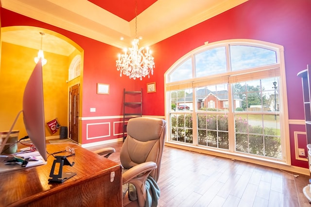 home office featuring hardwood / wood-style flooring, a towering ceiling, and an inviting chandelier