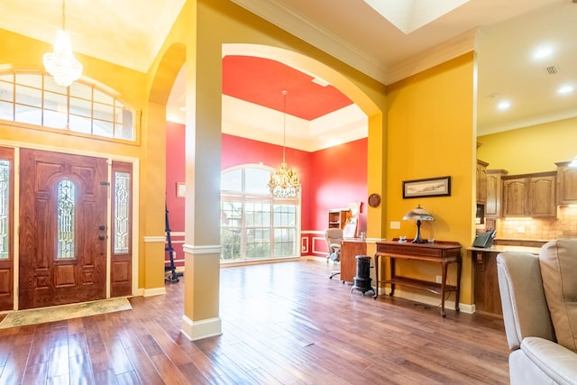 foyer entrance with a notable chandelier, dark hardwood / wood-style flooring, ornamental molding, and a high ceiling