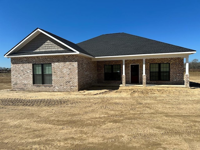 view of front of house with brick siding, covered porch, and a shingled roof