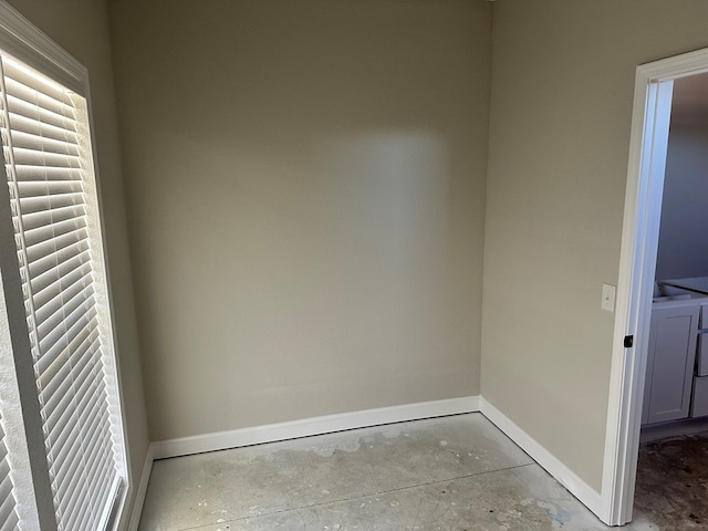 empty room with washer / clothes dryer, unfinished concrete flooring, and baseboards