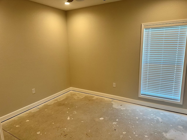 empty room featuring baseboards, unfinished concrete flooring, and ceiling fan