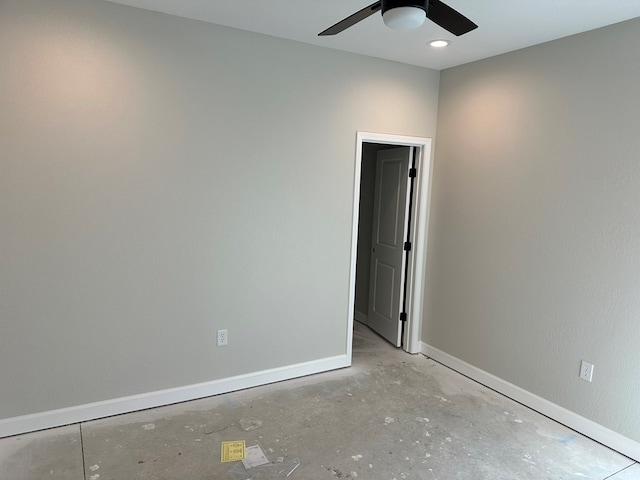 unfurnished room featuring baseboards, concrete flooring, and ceiling fan