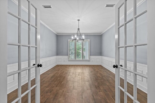 unfurnished room with visible vents, an inviting chandelier, crown molding, and a decorative wall
