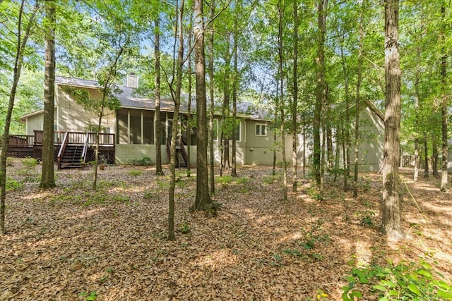 back of property featuring a sunroom, a deck, and a chimney