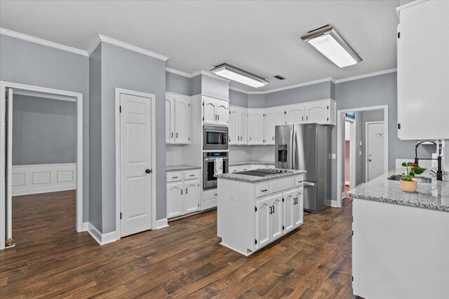 kitchen with ornamental molding, a sink, appliances with stainless steel finishes, and white cabinetry