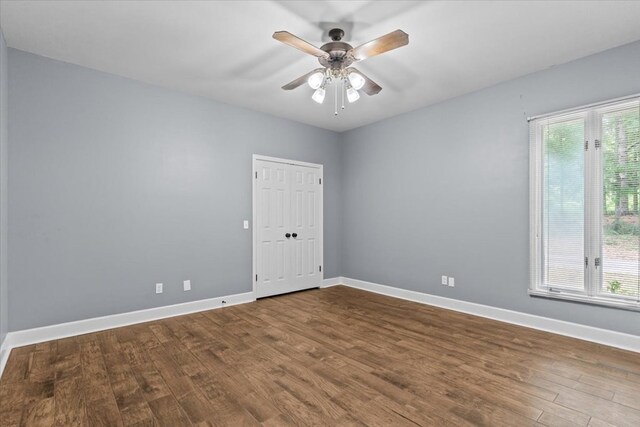 empty room featuring a ceiling fan, wood finished floors, and baseboards