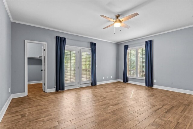 spare room with baseboards, wood finished floors, ceiling fan, and crown molding
