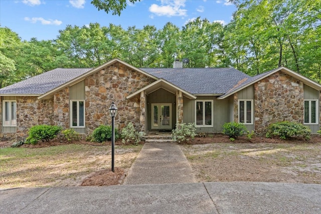 view of front of property with a shingled roof, french doors, and stone siding