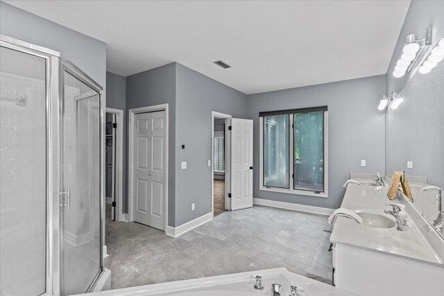 full bath featuring a sink, a stall shower, double vanity, and baseboards